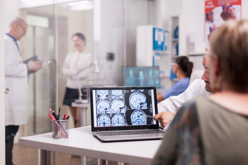 senior woman hospital office looking brain ct scan while discussing with doctor about diagnosis sick young woman elderly medic with grey hair clinic corridor